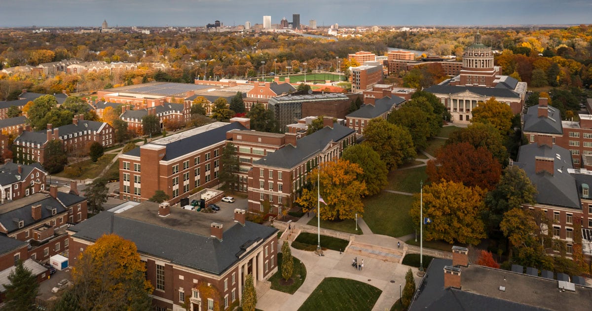 Aerial view of a university campus with brick buildings and autumn trees.