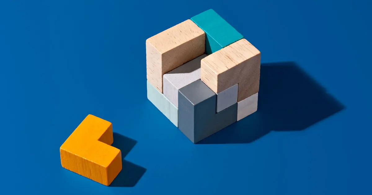 A wooden puzzle piece rests beside a vibrant blue block, showcasing a playful contrast in colors and textures.